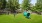 a large green park with a blue trampoline and trees